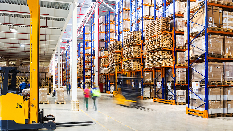 A large warehouse with multiple forklifts in motion
