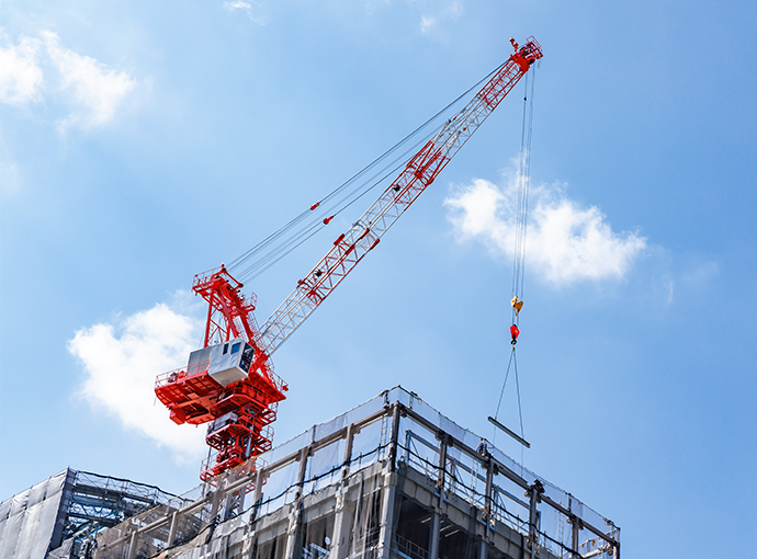 A crane lowering a bean onto a W. P. Carey owned building, against a bright blue sky.