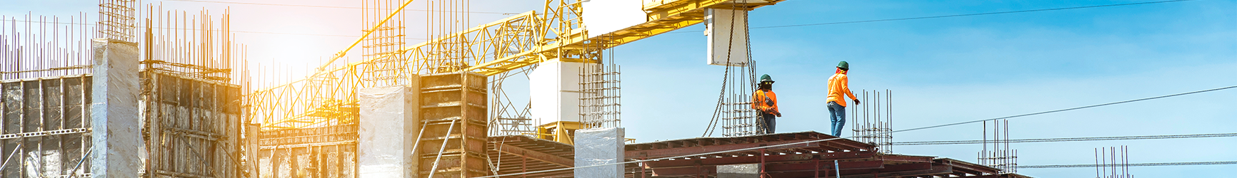 A construction site for a new building, with two workers standing atop the roof.