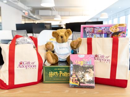 Two tote bags filled with gifts next to a teddy bear.