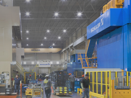 The inside of a W. P. Carey owned building, with a large blue wall, yellow machinery and employees walking.