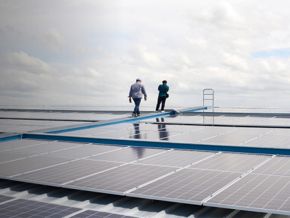 Two men walking atop rooftop solar panels on a cloudy day.